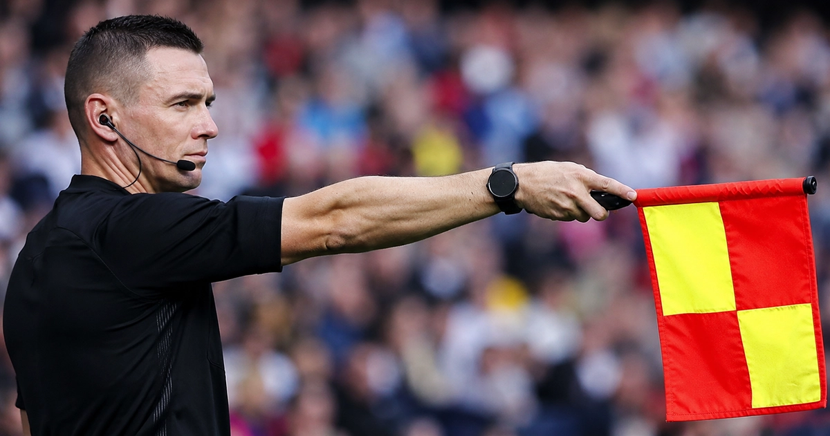 Fictitious assistant referee sprinting along the touchline with the offside flag raised, level with the defensive line