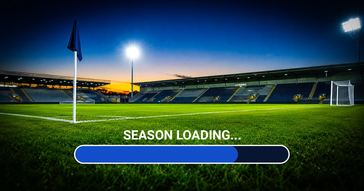 An empty floodlit football stadium at dusk with a 'Season loading...' progress bar graphic overlaid across the pitch, styled to look nearly complete